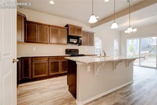 a kitchen with stainless steel appliances granite countertop a sink a stove and a wooden floors