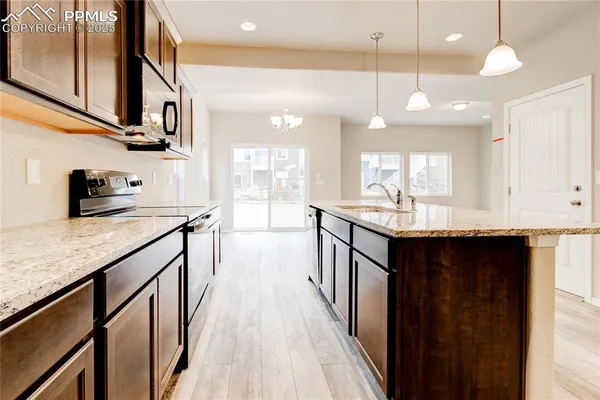 a kitchen with stainless steel appliances granite countertop a sink a stove and a wooden floors