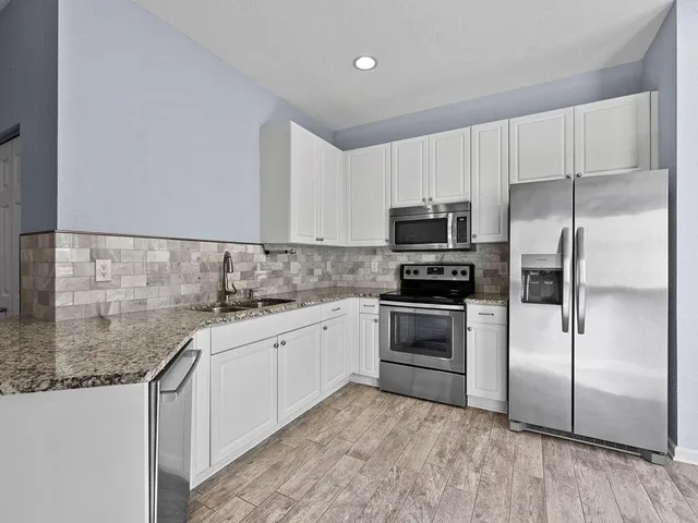 a kitchen with granite countertop a sink stainless steel appliances and counter space