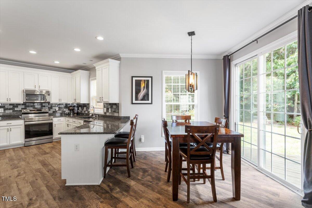 308 Mickleson Ridge Drive Raleigh, NC 27603 - Photo 14 of 51 a kitchen with kitchen island granite countertop wooden floor dining table and stainless steel appliances