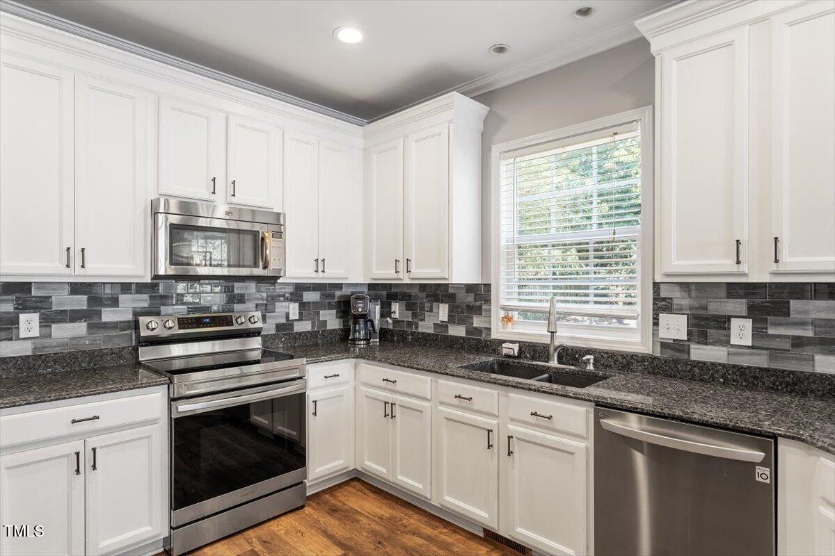 308 Mickleson Ridge Drive Raleigh, NC 27603 - Photo 17 of 51 a kitchen with granite countertop a stove sink and cabinets