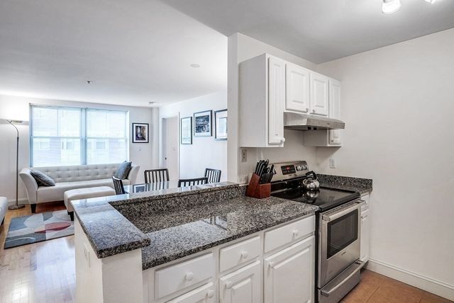 a kitchen with granite countertop a sink a stove and cabinets