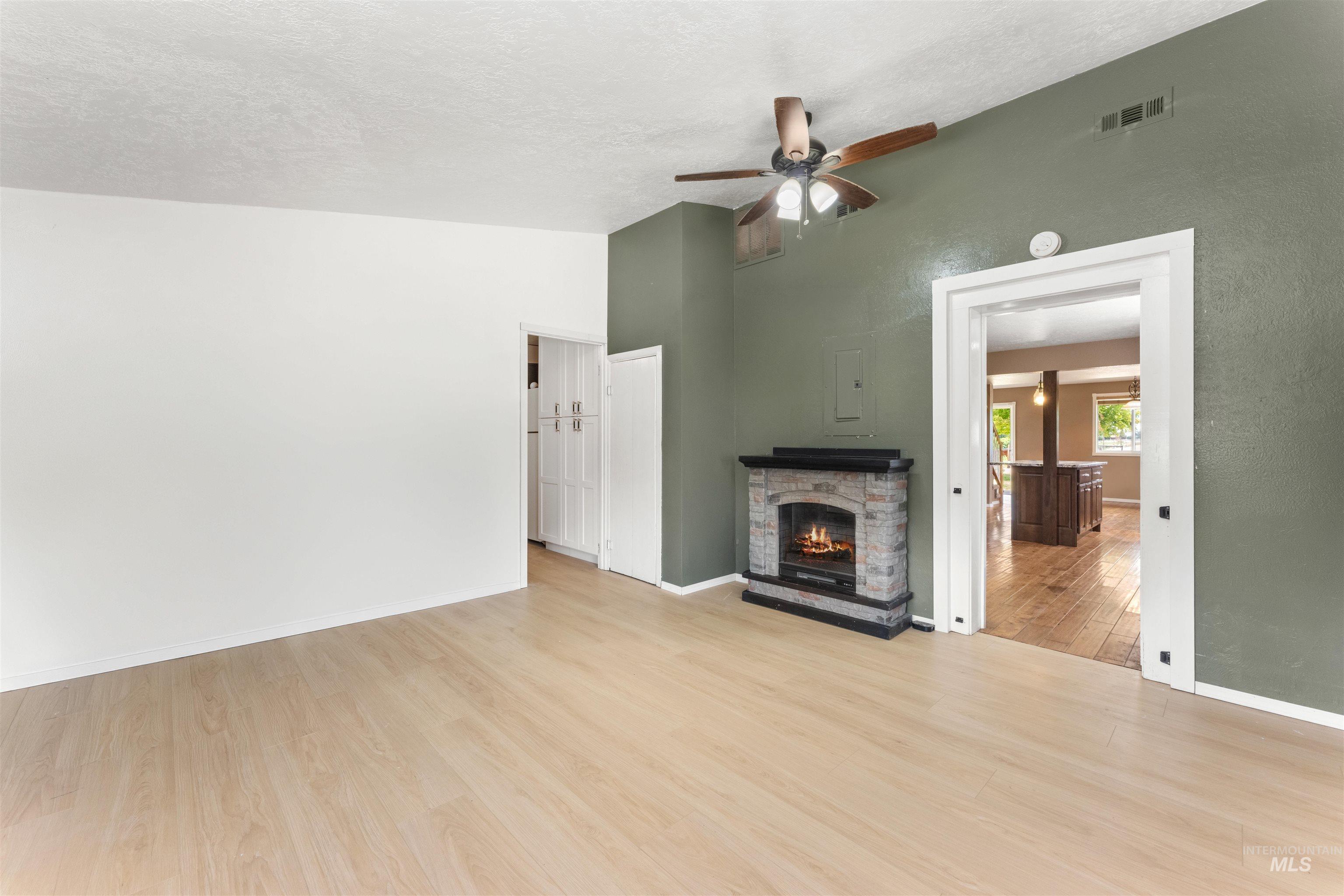 17441 Upper Pleasant Ridge Road Caldwell, ID 83607 - Photo 28 of 40 Open-concept living space featuring wood-finish flooring, a vaulted ceiling, and a stone-clad fireplace