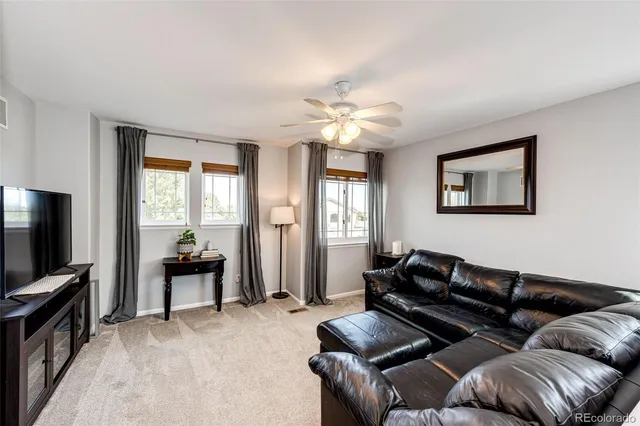 a living room with furniture ceiling fan and a window