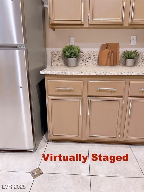 7640 Sierra Paseo Lane Las Vegas, NV 89128 - Photo 11 of 49 Kitchen with freestanding refrigerator, cream cabinets, light tile patterned flooring, and light stone countertops