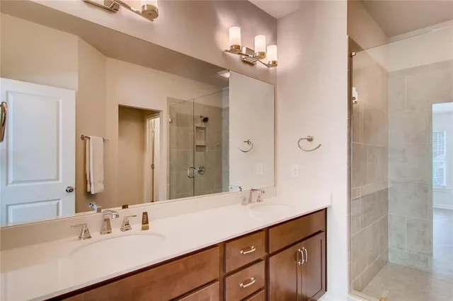 a bathroom with a double vanity sink a mirror and a shower