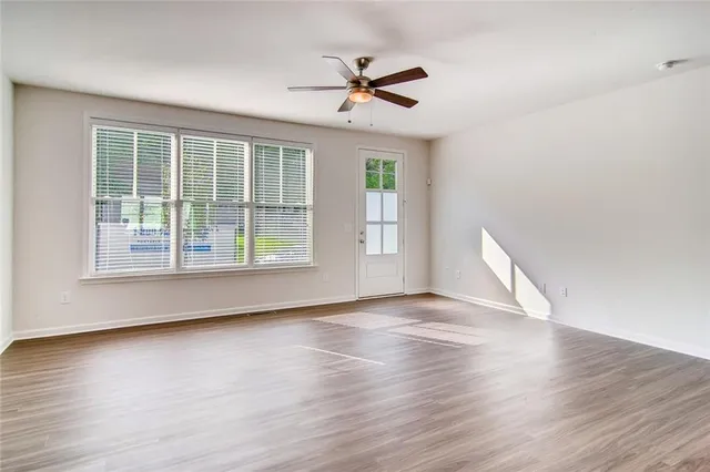 a view of an empty room with wooden floor and a window