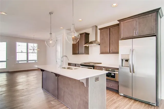 a kitchen with stainless steel appliances a refrigerator a sink a stove a microwave and wooden floor