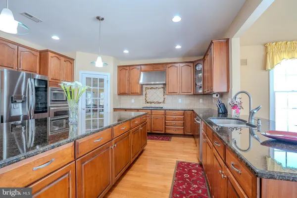 a kitchen with stainless steel appliances granite countertop a refrigerator and a stove top oven