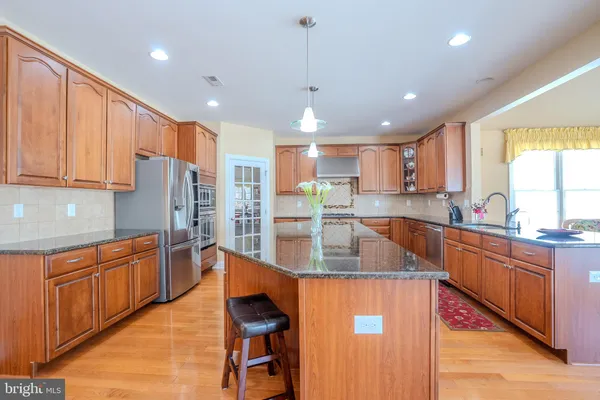 a kitchen with stainless steel appliances granite countertop a sink a stove and a refrigerator
