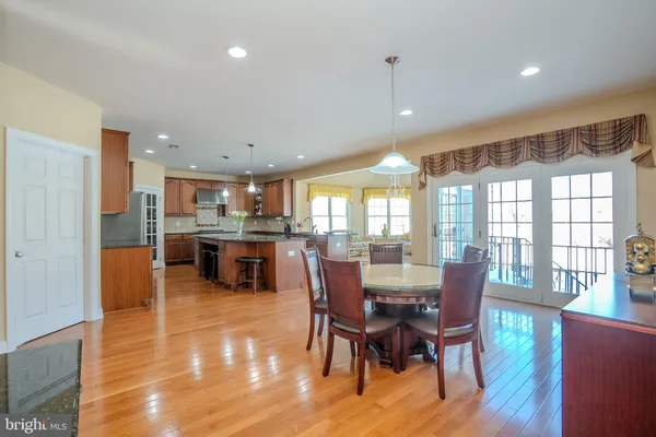 a dining room with wooden floor a chandelier a glass table and chairs