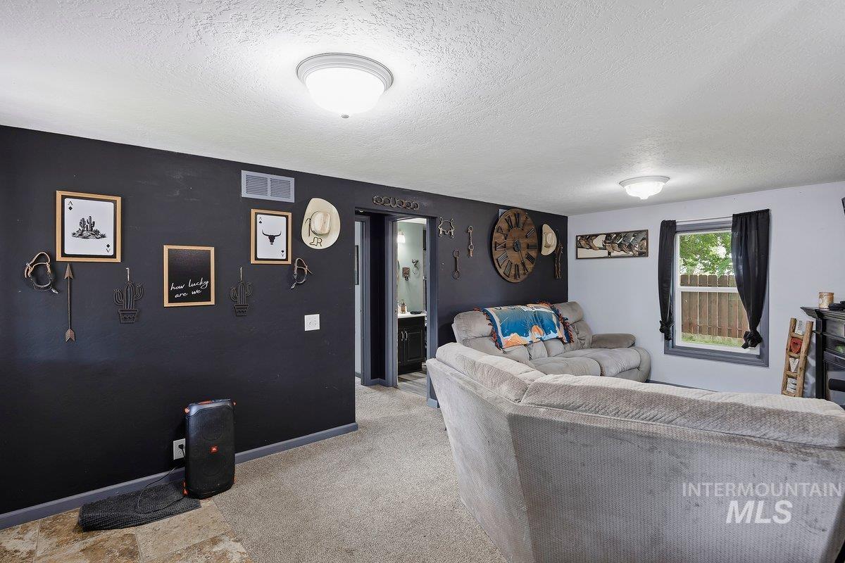418 South Date Street Shoshone, ID 83352 - Photo 5 of 36 Carpeted living area featuring a dark accent wall with framed art and wall decor