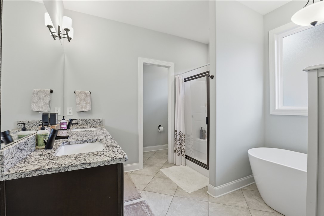127 West Stewart Street Pelzer, SC 29669 - Photo 9 of 23 This primary bathroom features a dual vanity, a spacious shower, and a freestanding soaking tub.