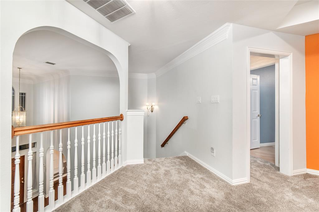 5801 Yeary Road Plano, TX 75093 - Photo 19 of 33 Carpeted upper-level landing featuring an arched opening, white balusters with a wood handrail, crown molding, and a built-in wall sconce