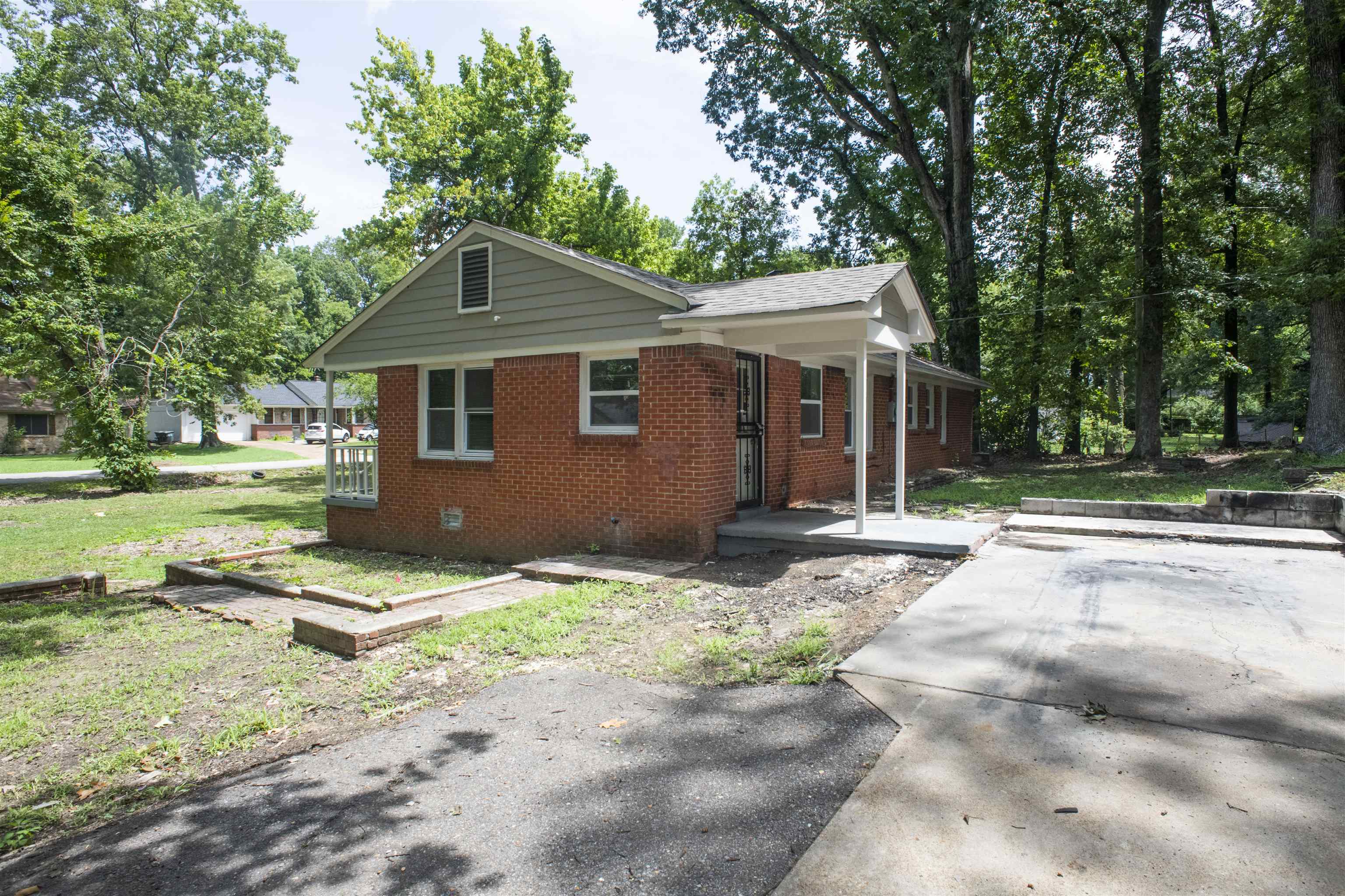 875 Enfield Road Memphis, TN 38116 - Photo 14 of 14 Brick exterior with a covered porch, white columns, and a concrete driveway