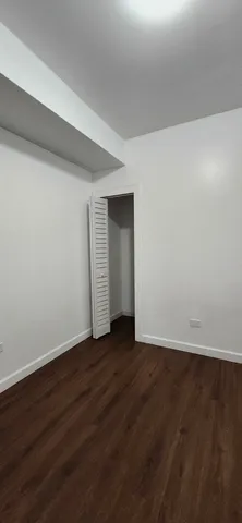 a view of an empty room with wooden floor and closet