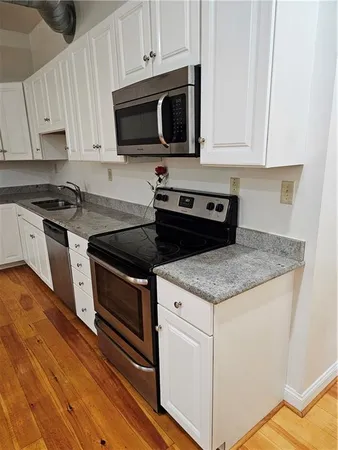 a kitchen with granite countertop a sink stainless steel appliances and cabinets