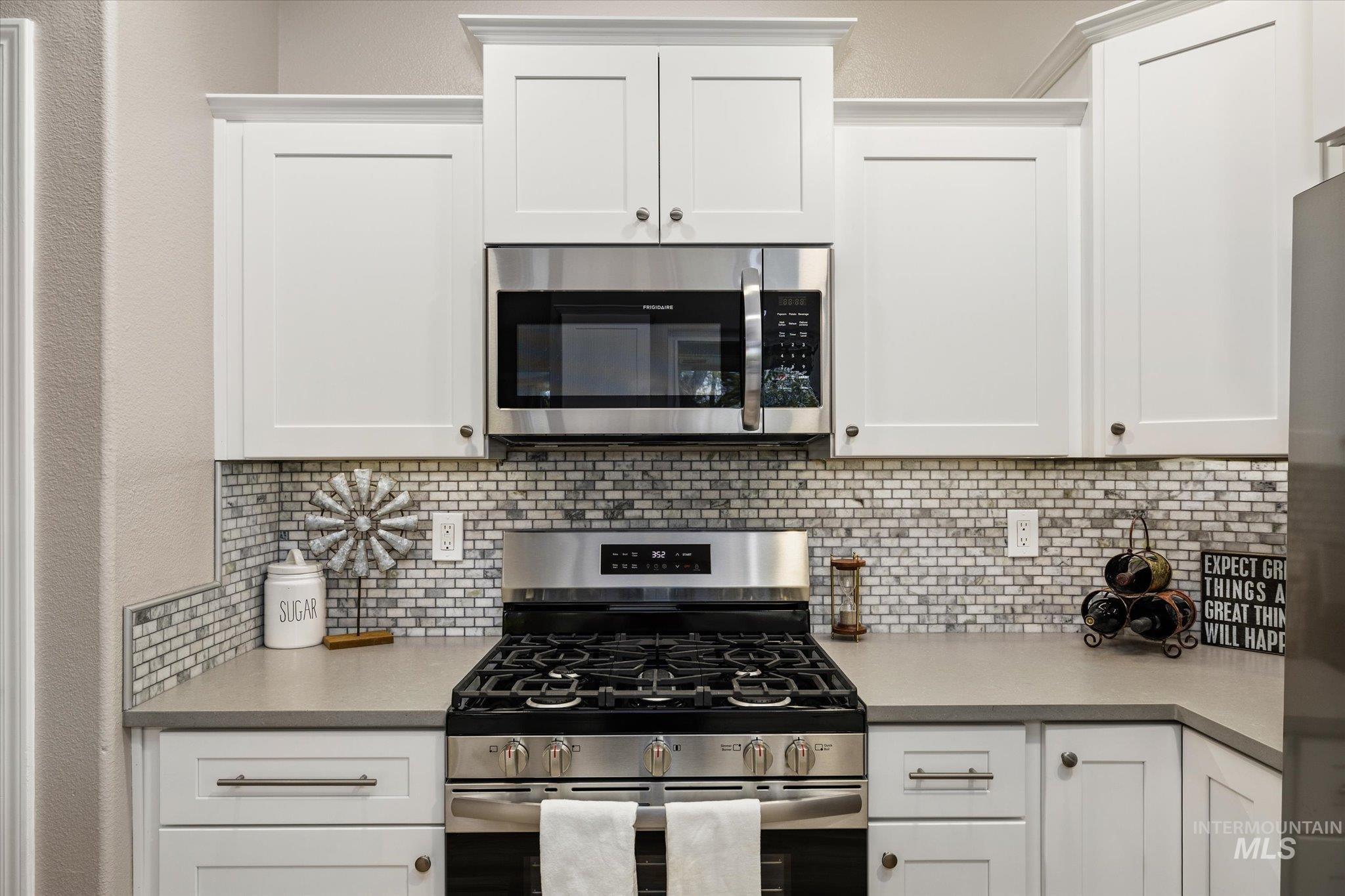 2250 North Amethyst Avenue Meridian, ID 83646 - Photo 19 of 50 Kitchen featuring stainless steel appliances, white cabinets, light countertops, and decorative backsplash