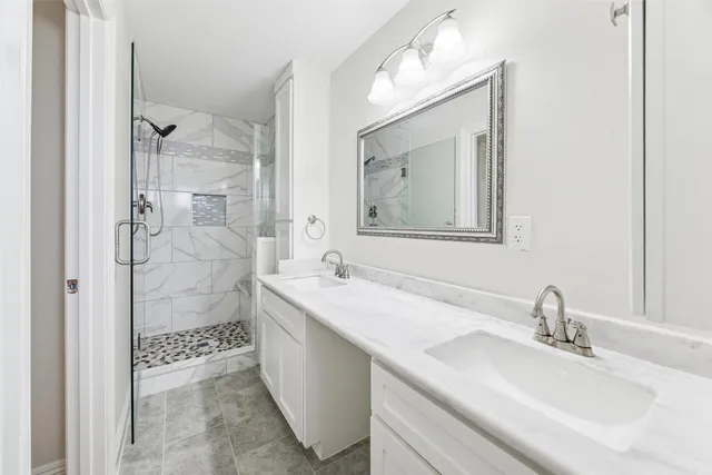 a bathroom with a granite countertop sink mirror and shower