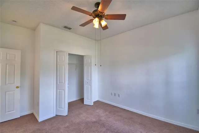 an empty room with windows and chandelier fan