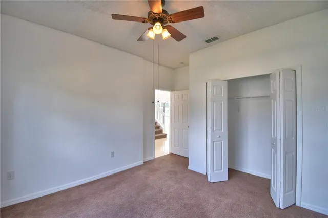 an empty room with closet and a chandelier fan