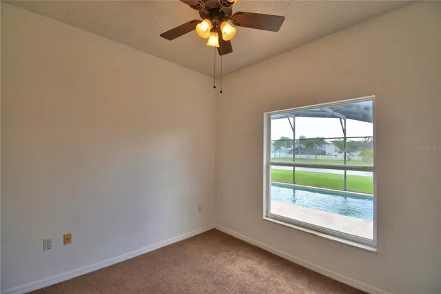 an empty room with a window and a fan