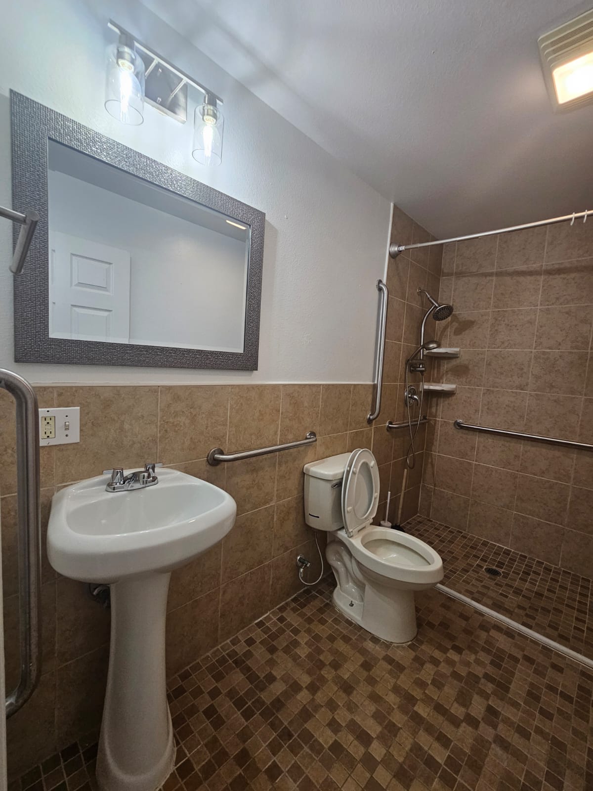 606 Trinity Street Lockhart, TX 78644 - Photo 12 of 23 Functional bathroom featuring accessibility handrails and tiled shower area.