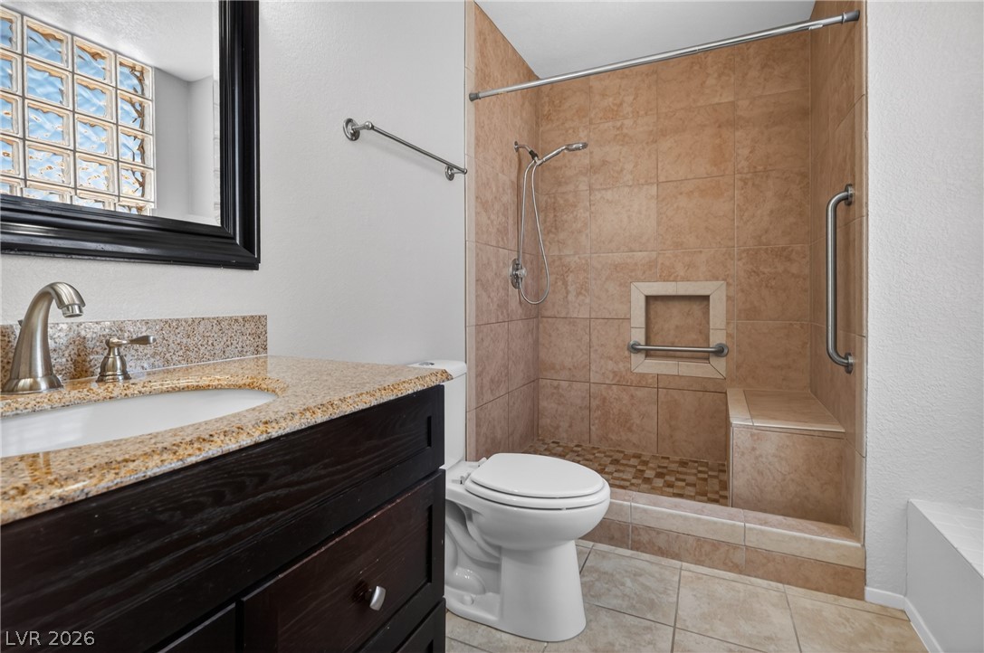 2241 Highpointe Drive, Unit 101 Laughlin, NV 89029 - Photo 21 of 23 This bathroom features a granite counter, a modern vanity, and a tiled shower with a built-in bench.