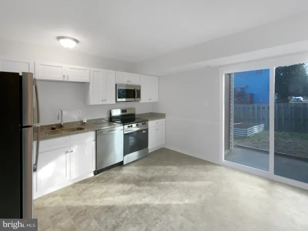 a kitchen with granite countertop a refrigerator and a stove top oven