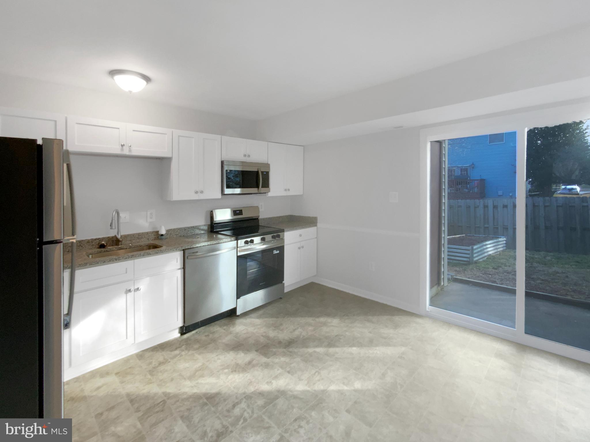 5132 Redbud Road Fredericksburg, VA 22407 - Photo 7 of 19 a kitchen with granite countertop a refrigerator and a stove top oven
