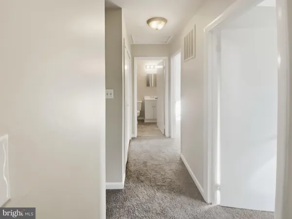 a view of a hallway with white walls and a window