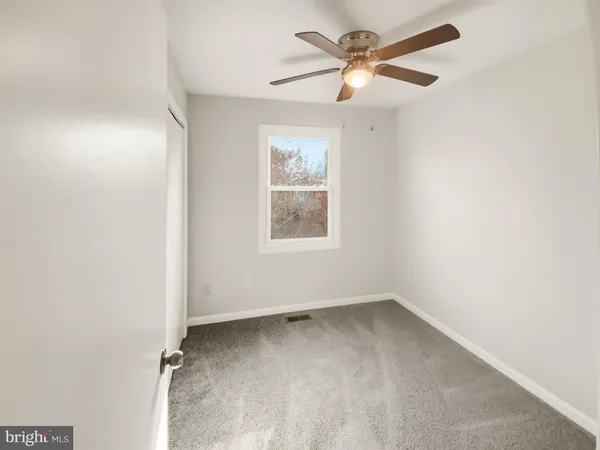 an empty room with a window and a fan