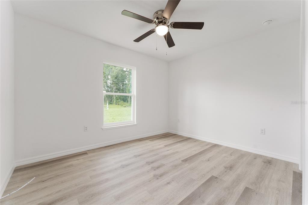 319 Fisher Road Ocklawaha, FL 32179 - Photo 35 of 48 an empty room with wooden floor ceiling fan and windows
