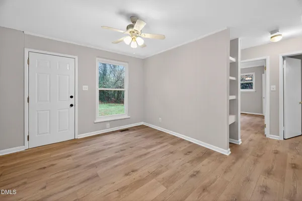 a view of an empty room with wooden floor and a window