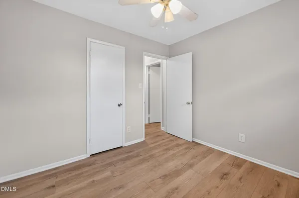 an empty room with wooden floor and chandelier fan
