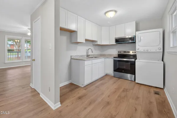 a kitchen with stainless steel appliances granite countertop a stove top oven a sink dishwasher and a refrigerator with wooden floor