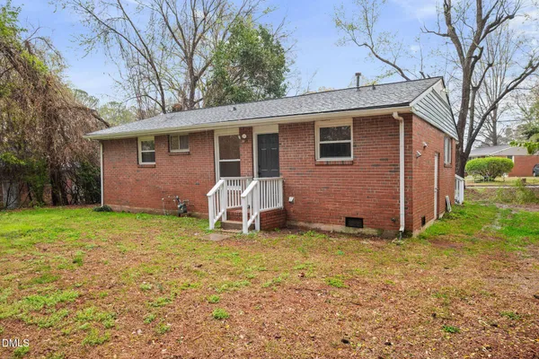 a view of a house with a yard and chairs