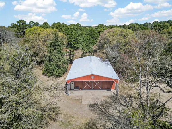 a view of a dry yard with a barn in the background