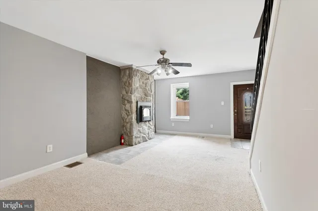 an empty room with chandelier fan and windows