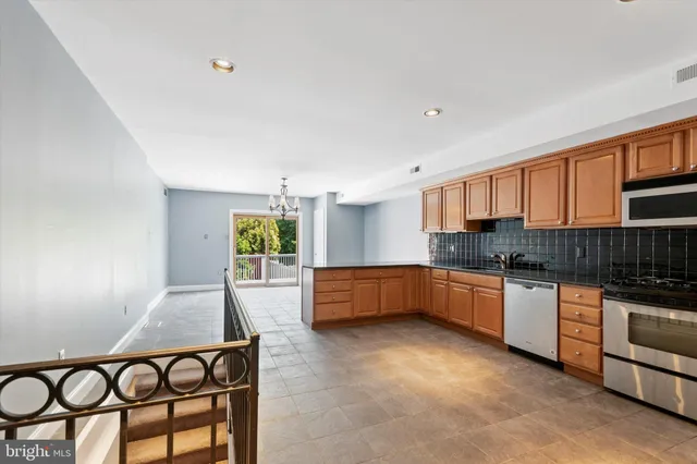 a kitchen with stainless steel appliances granite countertop a stove a sink dishwasher a microwave oven and a dining table with wooden floor