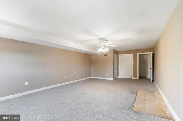 an empty room with chandelier fan and windows