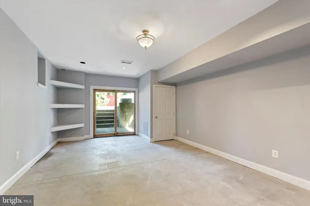 a view of an empty room with a window and cabinet