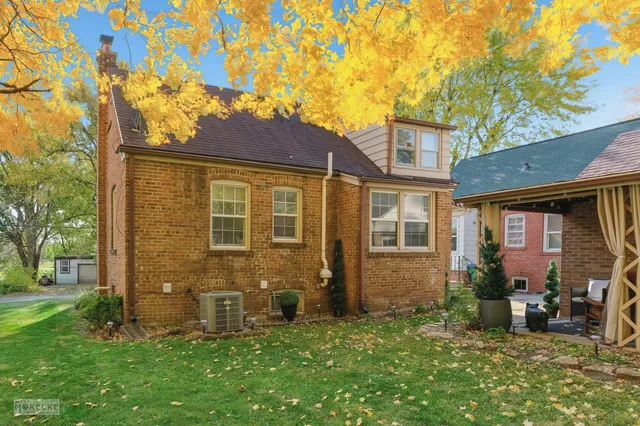 a view of a brick house with many windows and a large tree