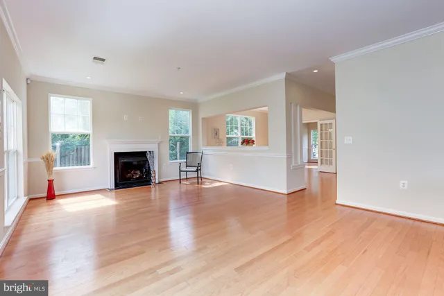 an empty room with wooden floor fireplace and windows