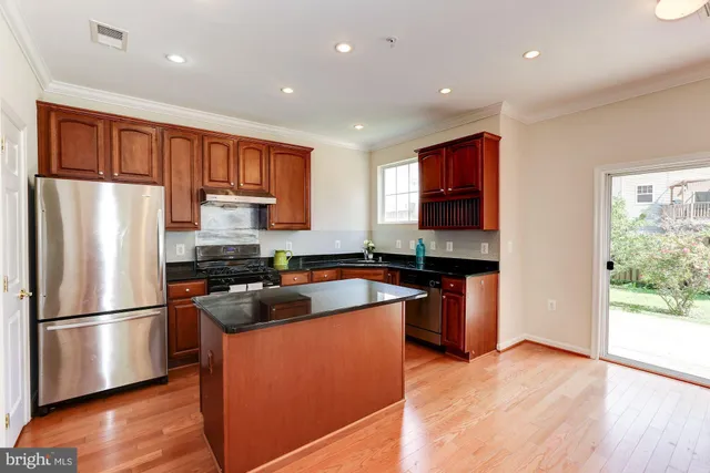 a kitchen with stainless steel appliances granite countertop a refrigerator sink and wooden floor