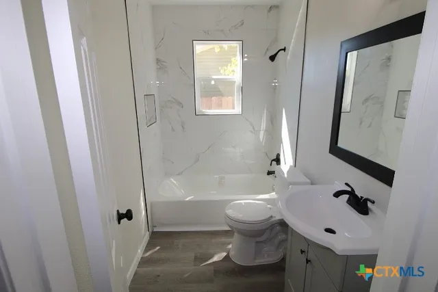 a bathroom with a bathtub shower sink vanity mirror and toilet