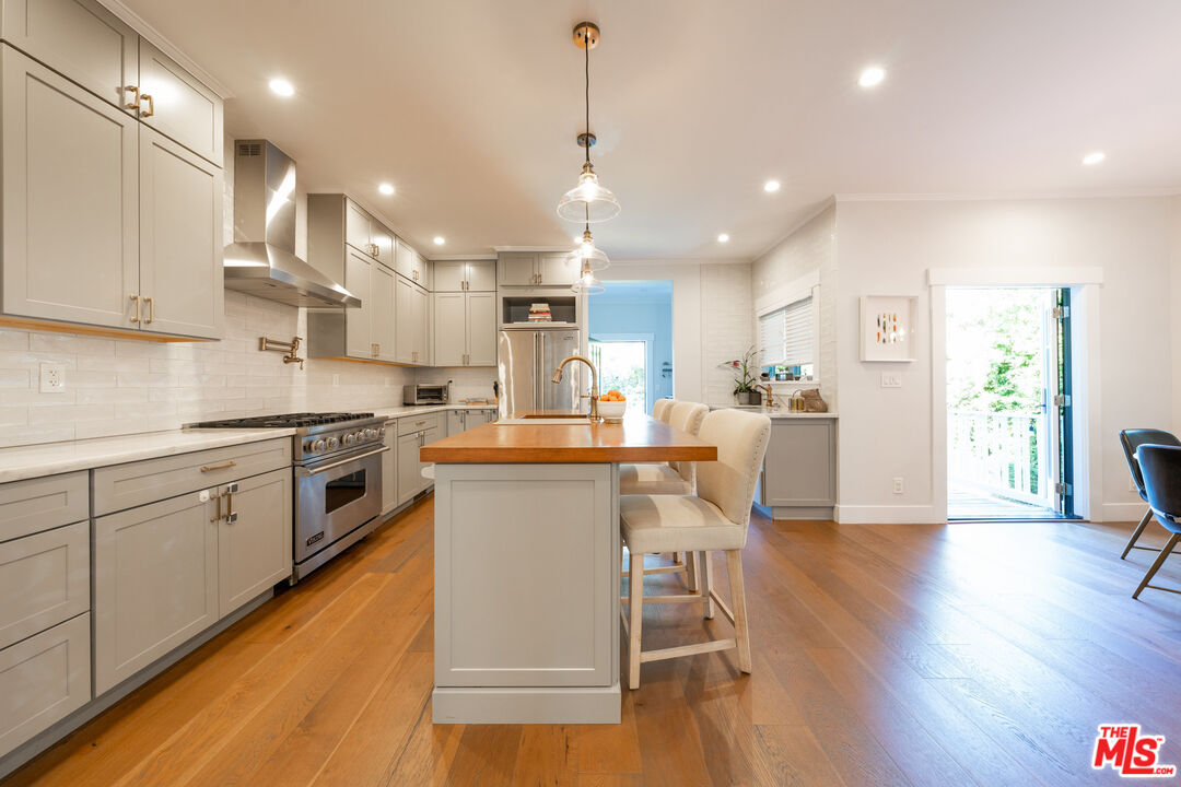 385 North Wilton Place Los Angeles, CA 90004 - Photo 15 of 53 a kitchen with stainless steel appliances kitchen island granite countertop a stove a sink a refrigerator and white cabinets with wooden floor