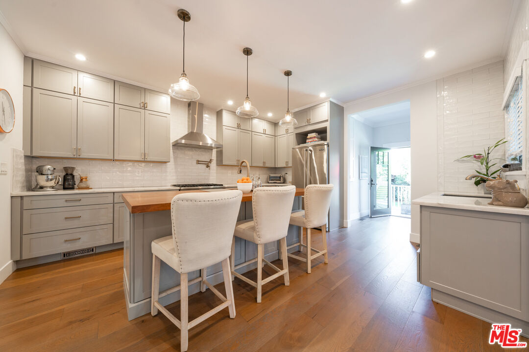 385 North Wilton Place Los Angeles, CA 90004 - Photo 16 of 53 a kitchen with stainless steel appliances a dining table chairs sink and cabinets