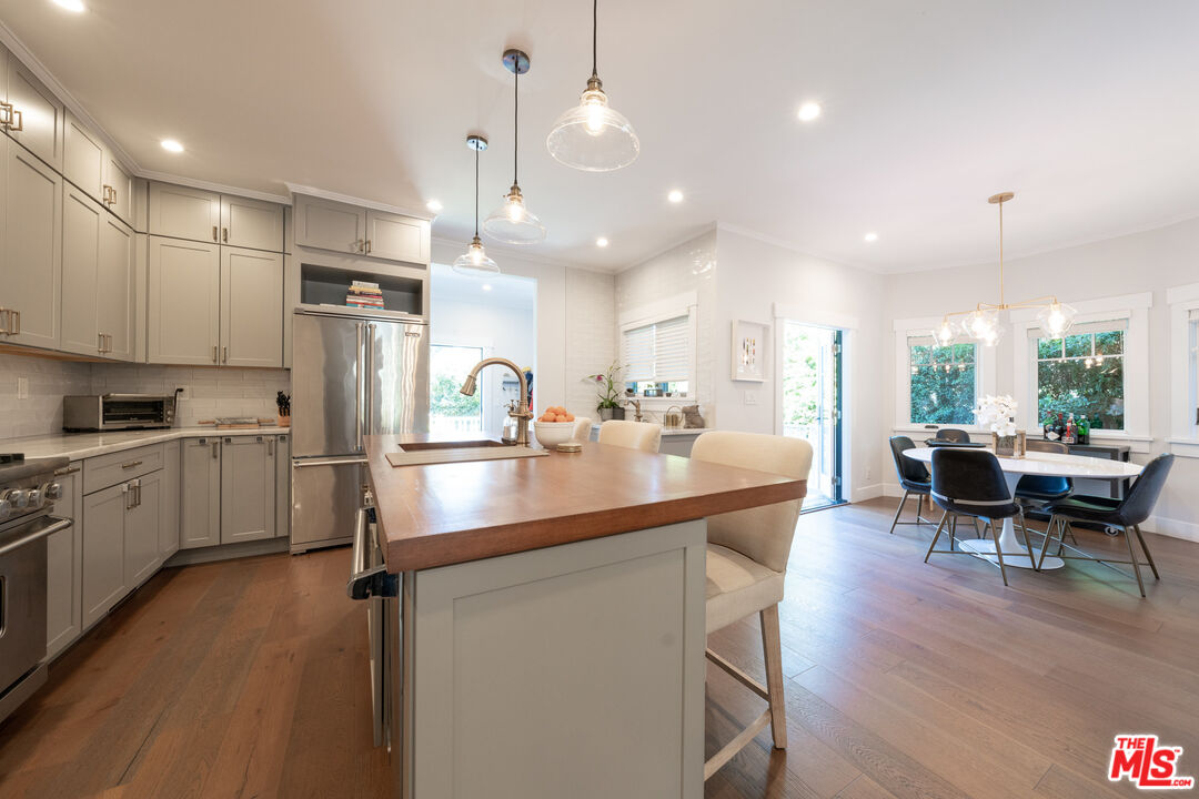 385 North Wilton Place Los Angeles, CA 90004 - Photo 18 of 53 a kitchen with stainless steel appliances a table chairs refrigerator and cabinets