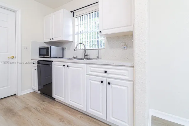 a kitchen with white cabinets and window